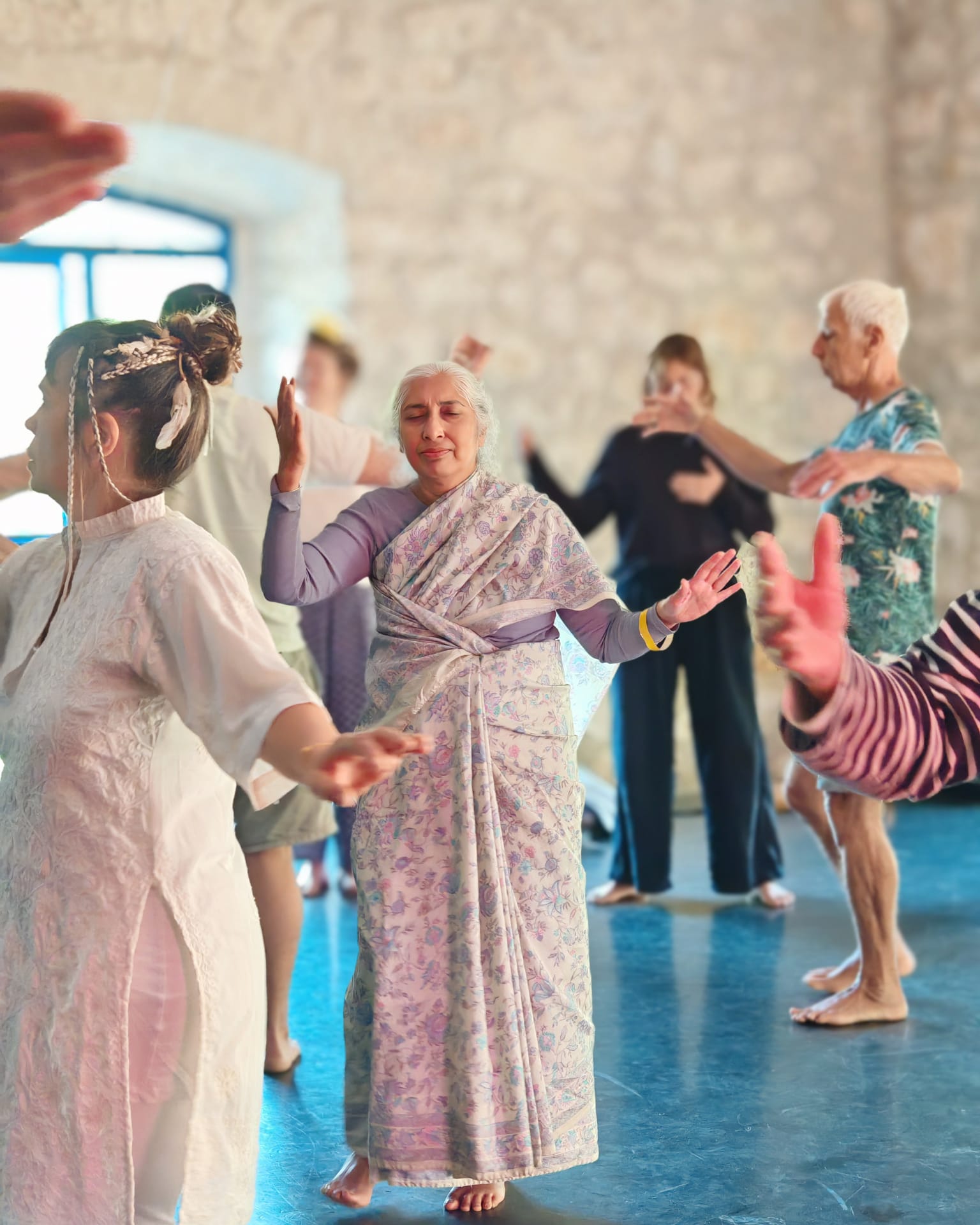 Yashi guidant un atelier de danse méditative dans une salle lumineuse aux murs de pierres